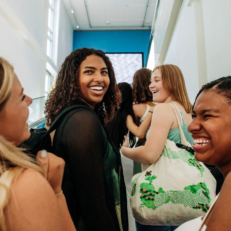 A group of female students are chatting and laughing as they walk down a corridor 800