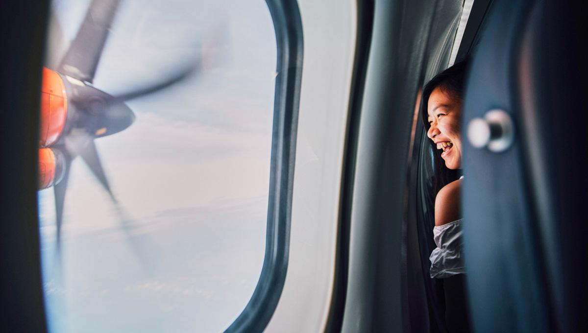 A happy woman smiles as she looks out the airplane window