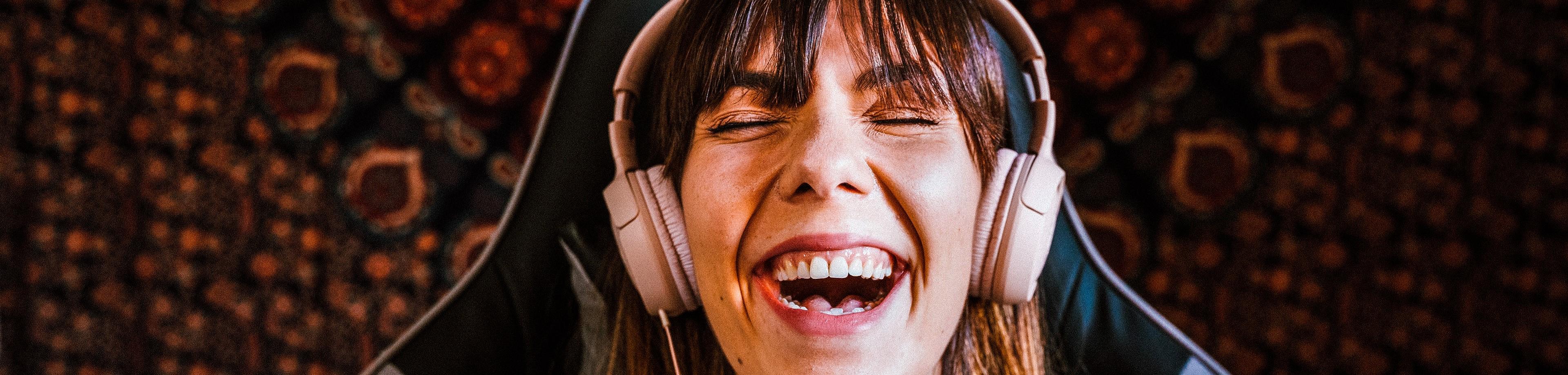Young woman laughing as she listens to something on headphones and holds her smarphone