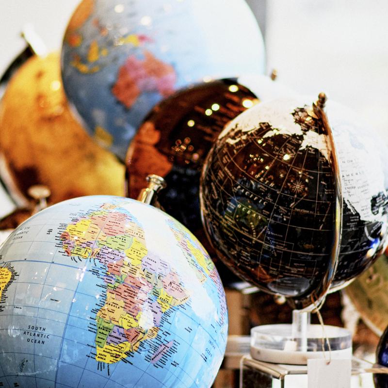 Close up of several globe maps of the world on a desk