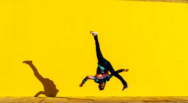 Full length of person jumping against yellow wall