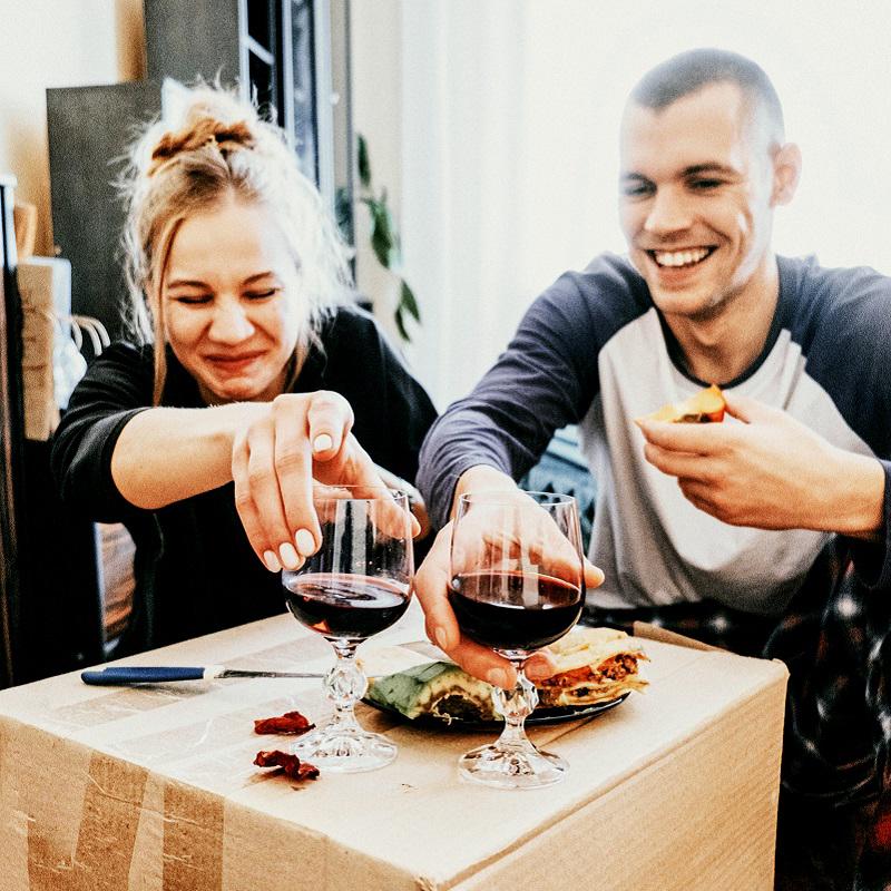 Happy man and woman wine and dine from a cardboard box