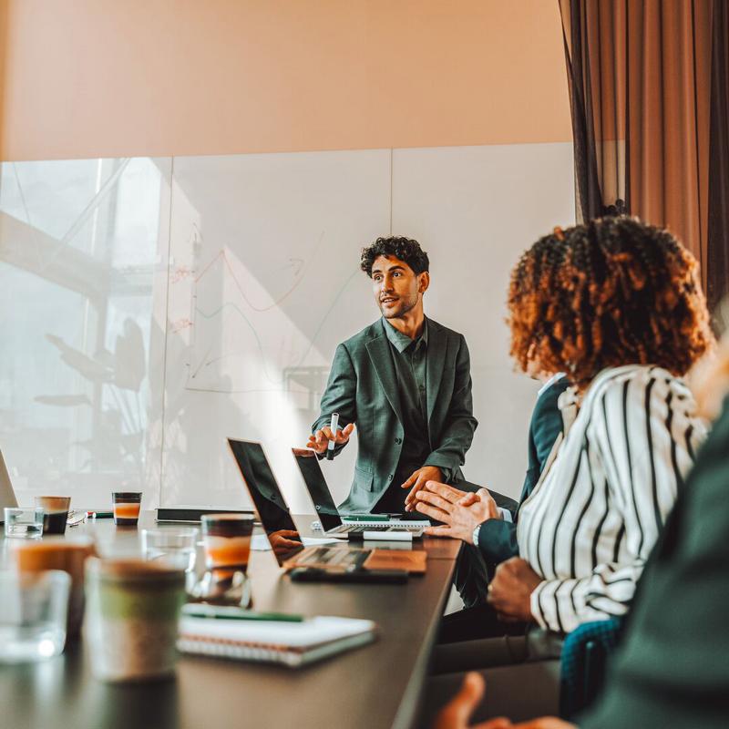 Man presents to co workers in meeting room