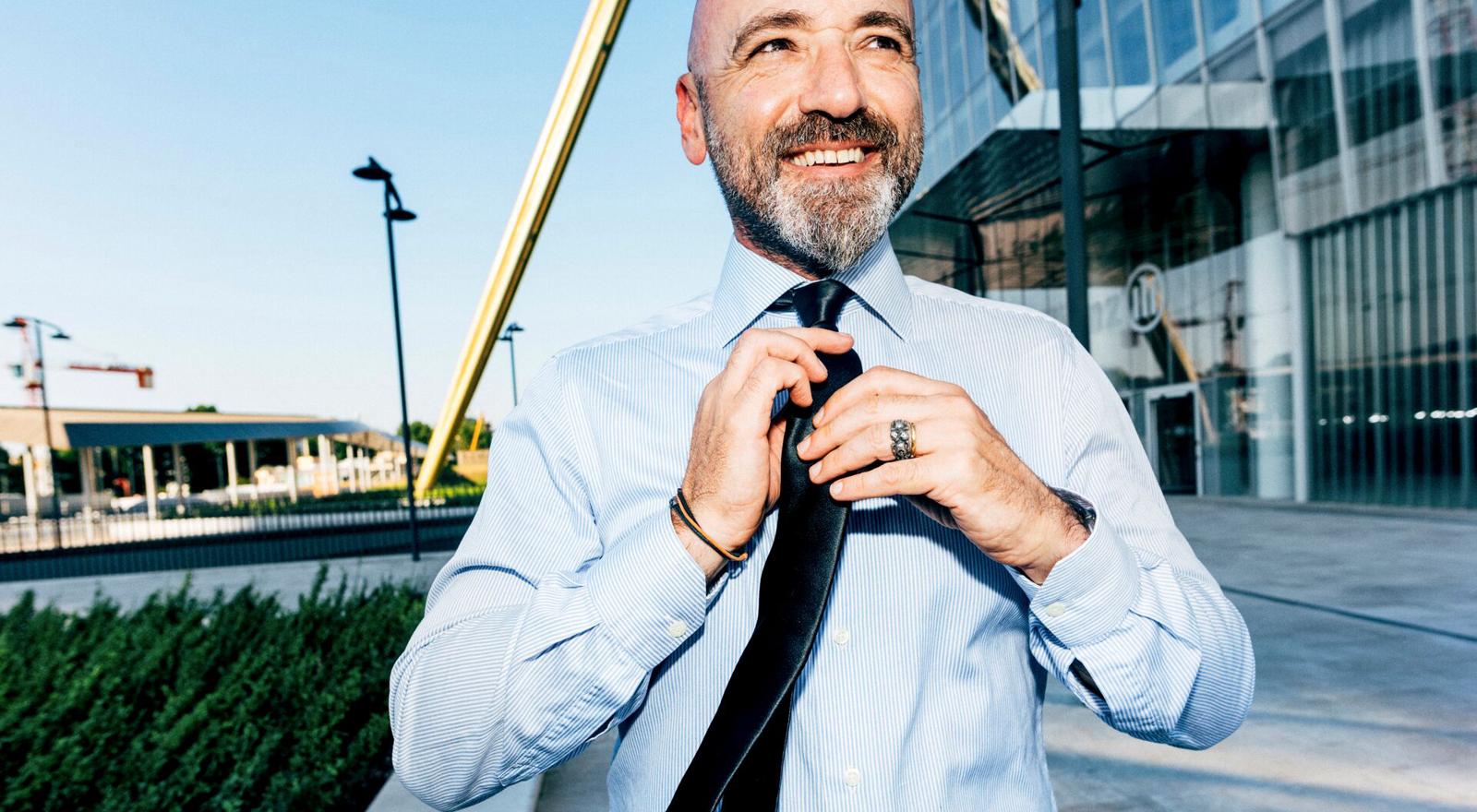 Large Web and Screen A smiling man adjusts his tie in front of an office building