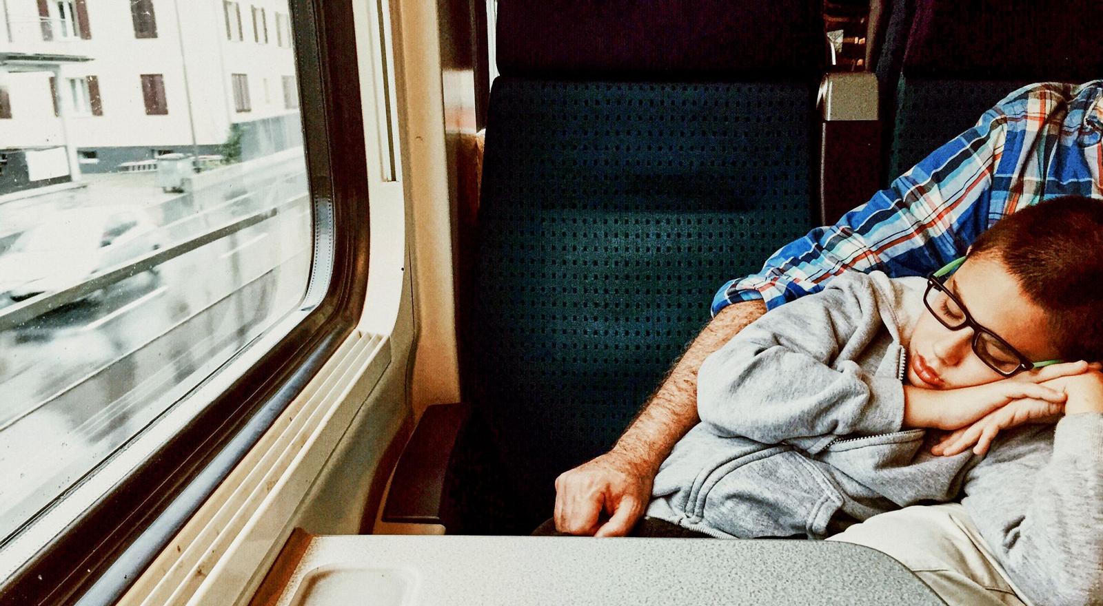 Large Web and Screen A young boy sleeps in his father's arms on the train