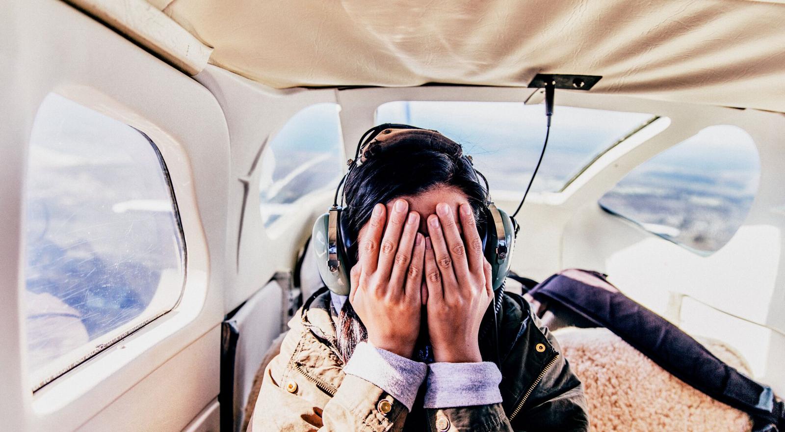 Large Web and Screen Frightened woman covers face in back seat of light aircraft.