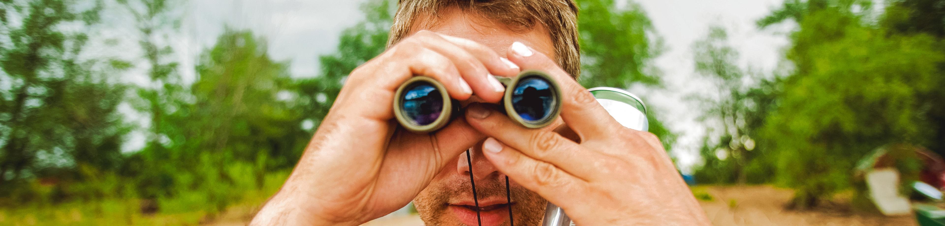 Man looks through binoculars in nature