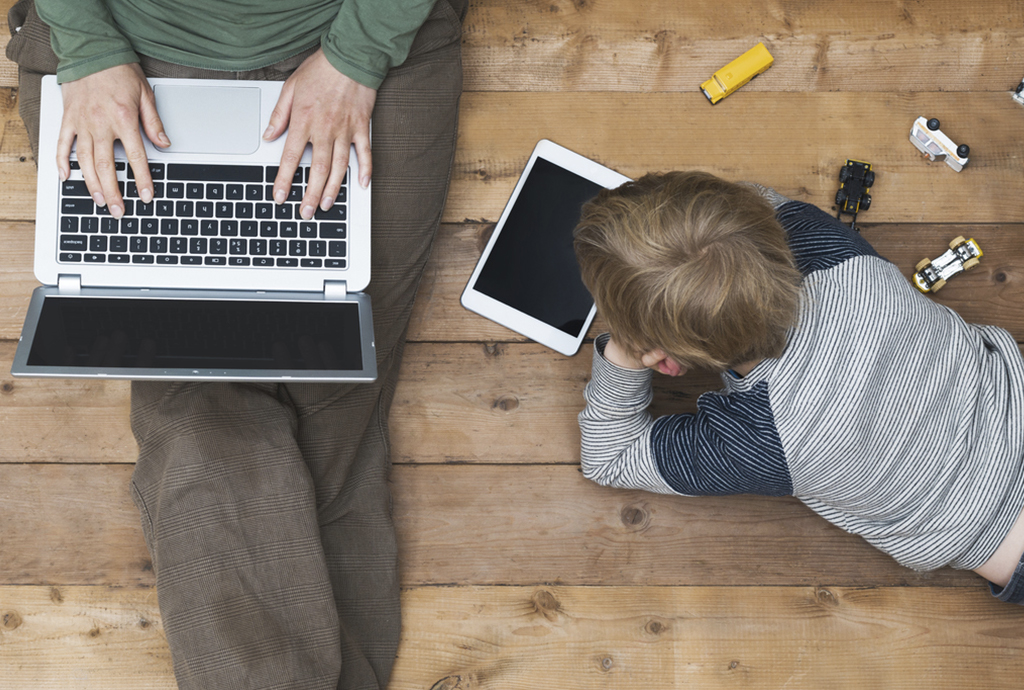 Dad and his son are texting on laptop and tablet