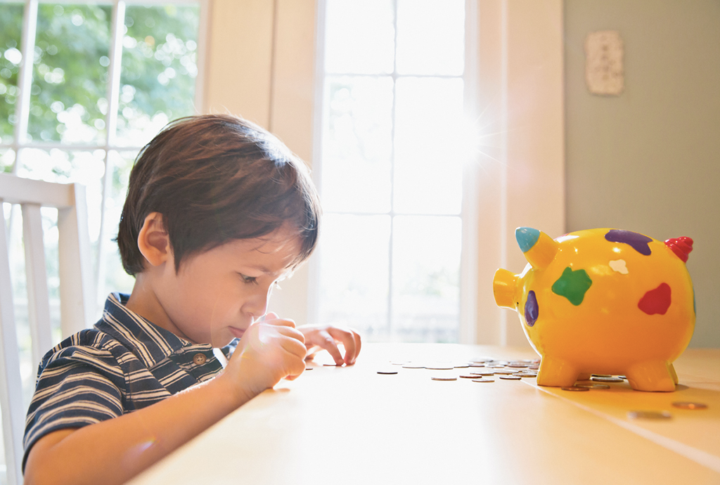 Child is couting his coin next to his piggy bank