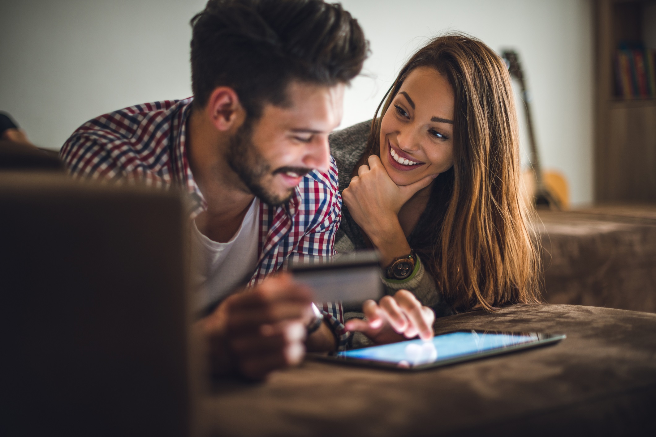 Couple are smiling each other while he working on tablet