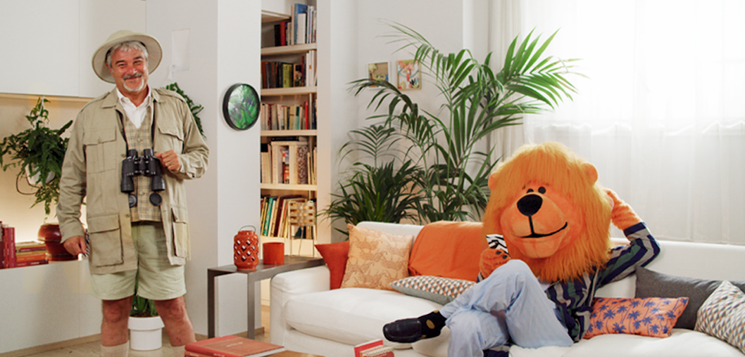 An archaeologist and a lion mascot are smiling in front of the camera