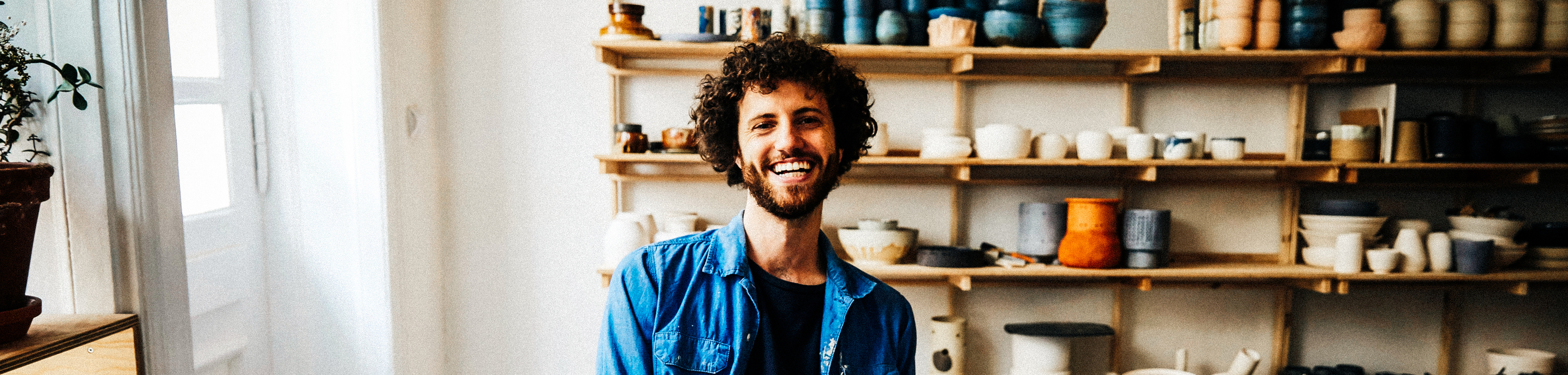 Portrait of happy young man sitting at table making pottery Z