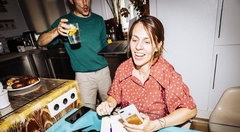 Smiling woman looking at her phone in the kitchen