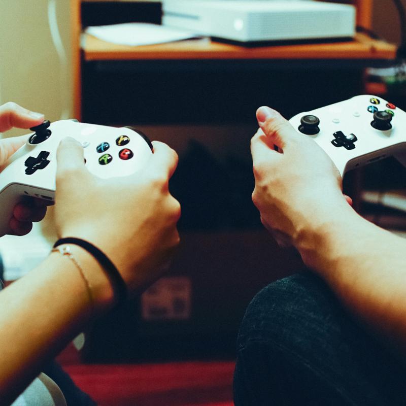 Two persons playing video game with controllers focus