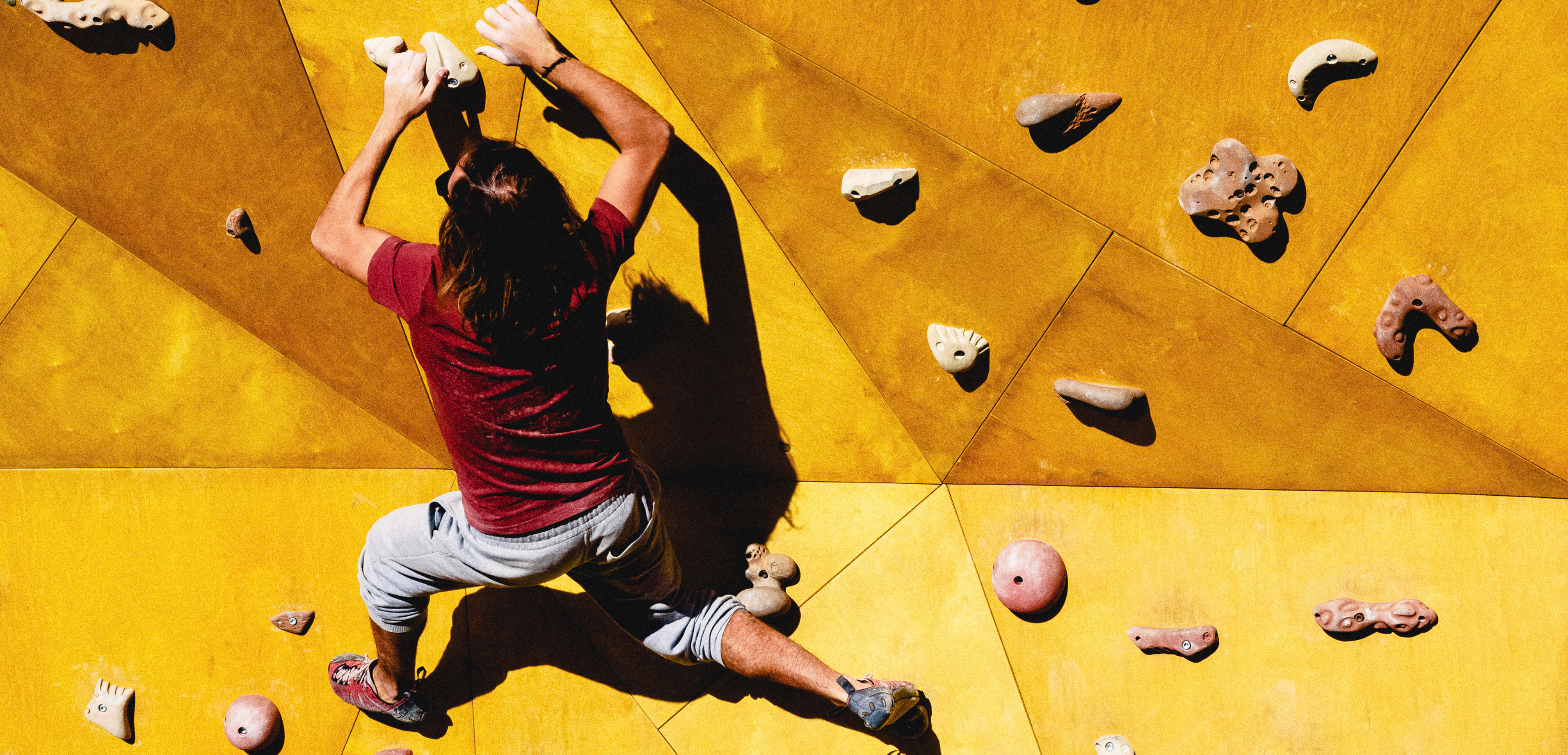Young man climbs on outdoor climbing wall 3840x1840