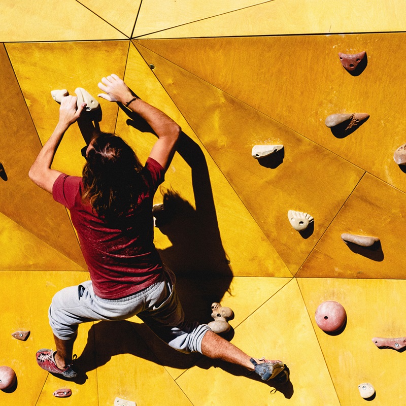Young man climbs on outdoor climbing wall 800x800