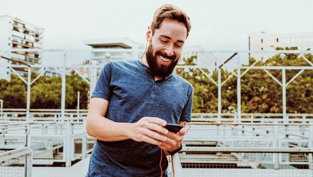 Young man using smart phone while standing against buildings